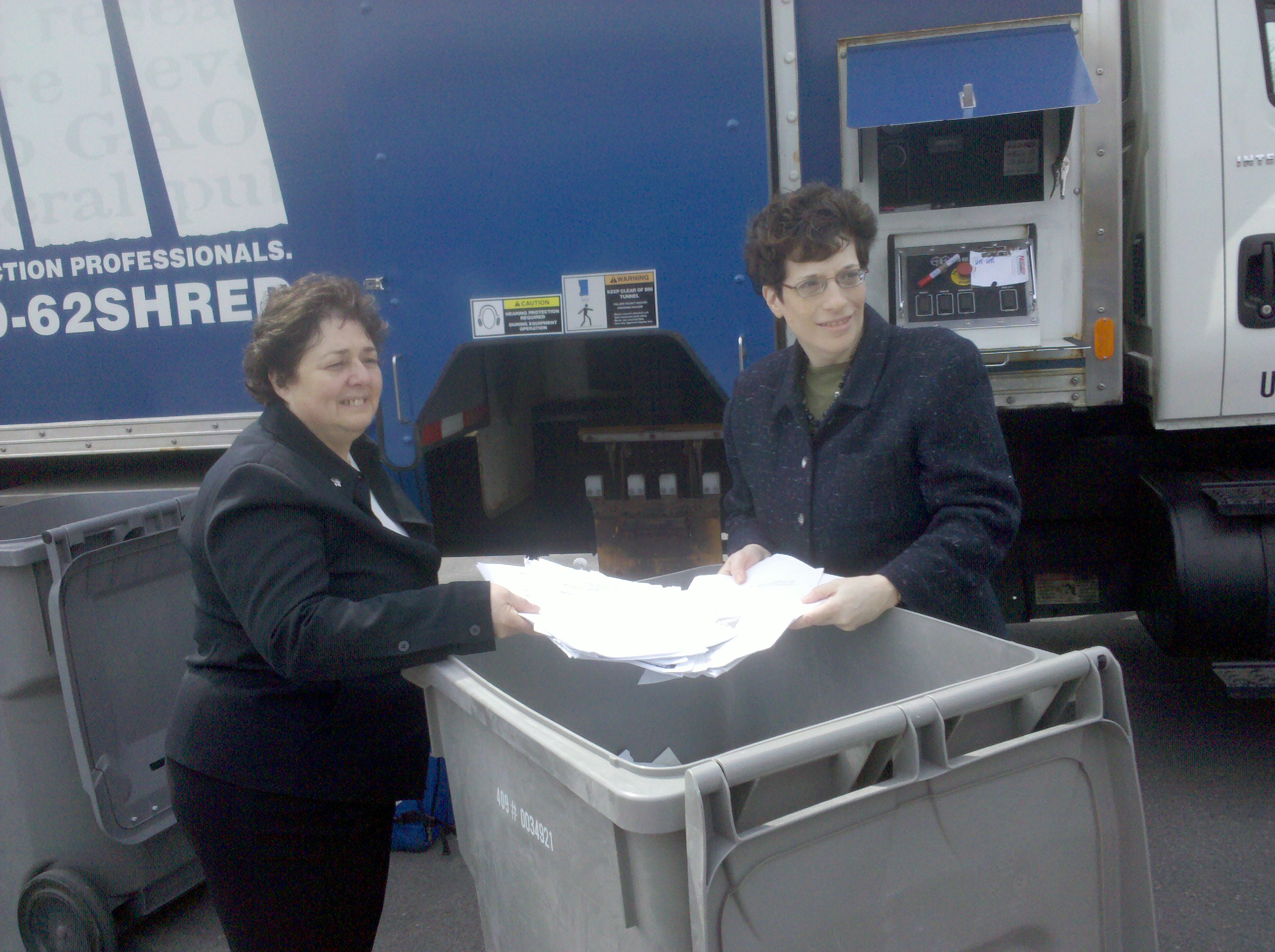 CPB Chairperson and Executive Director Mindy A. Bockstein and NY Assemblywoman Destito placing papers nito a garbage can for shredding